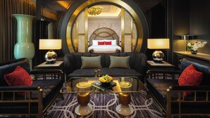 Una lujosa habitación de hotel con una cama grande, un sofá, una mesita de café y dos lámparas.