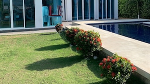A modern two-story house with a swimming pool, large windows, and a well-maintained lawn.