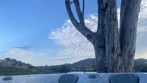 A hot tub area with a large tree and a view of a hilly landscape. - Unique Adobe Sanctuary w/hot tub close to hiking trails & wineries (San Marcos)