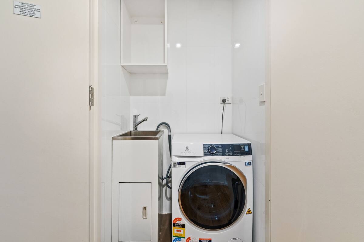 A compact laundry room with a washing machine and a small sink.