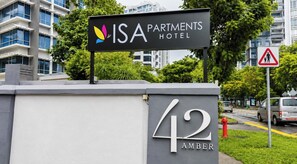 Cartell de l'Hotel ISA Partments amb un edifici modern al fons.