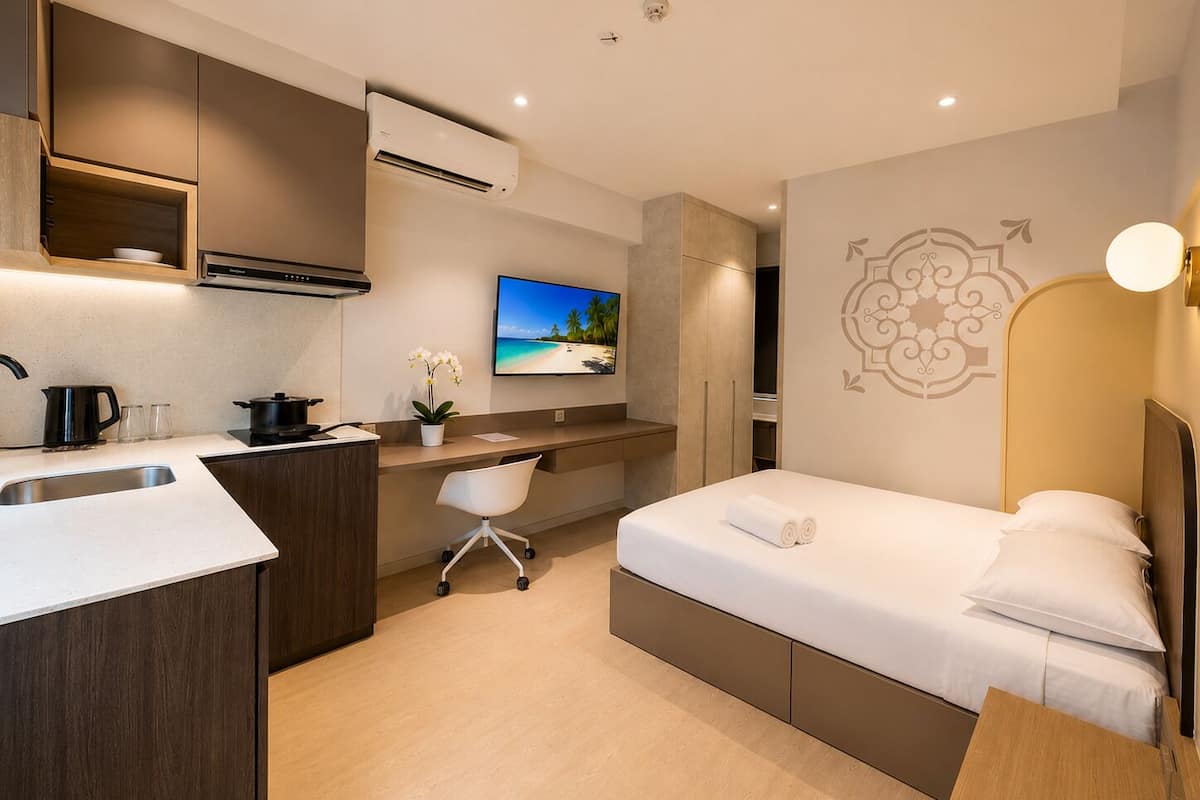 Une chambre d’hôtel moderne équipée d’une kitchenette, d’un lit, d’un bureau et d’une télévision.