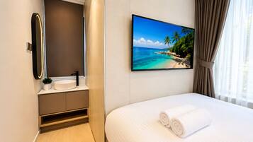 A hotel room with a bed, a bathroom with a sink, and a large window with curtains.