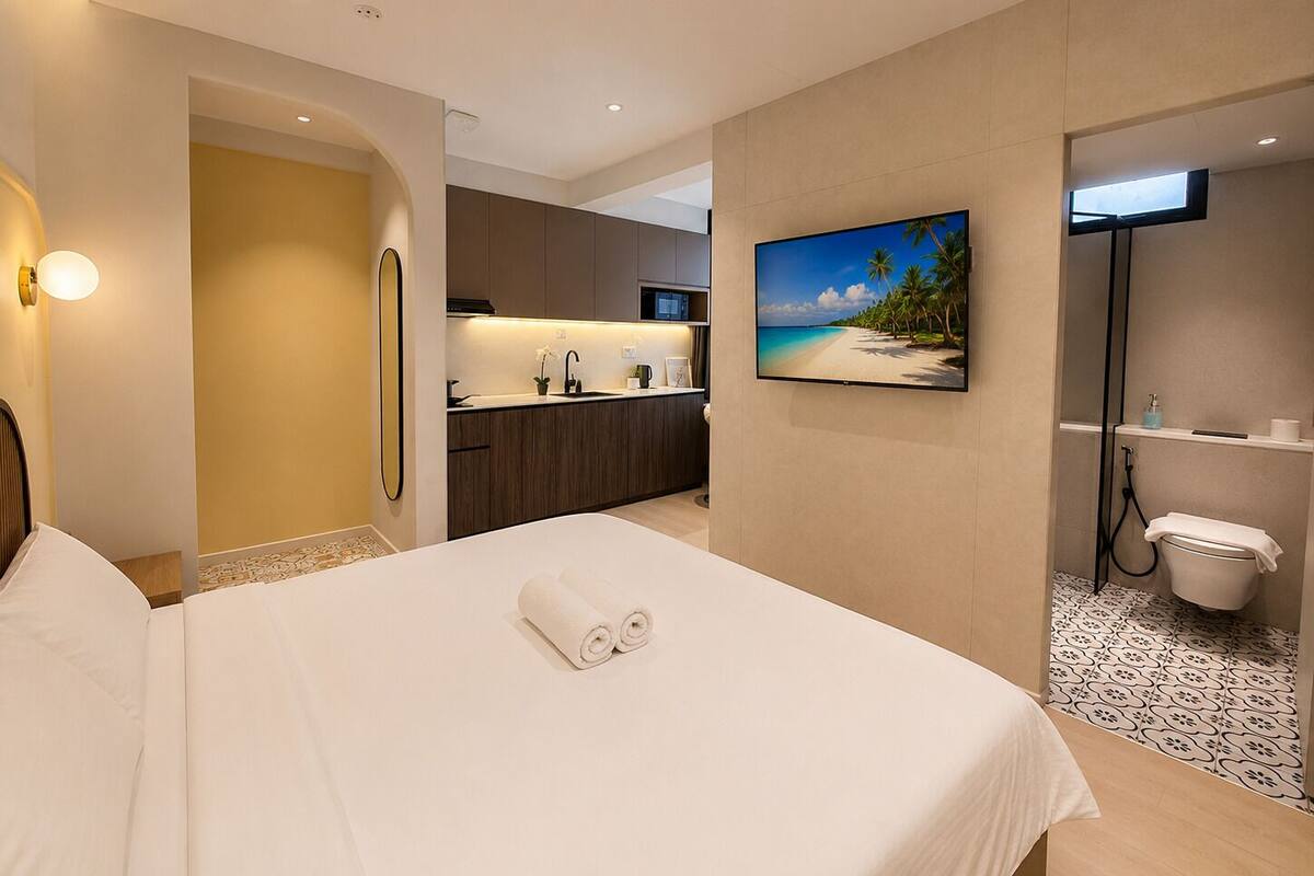 Une chambre d’hôtel équipée d’un lit, d’une salle de bain, d’une kitchenette et d’un téléviseur fixé au mur.
