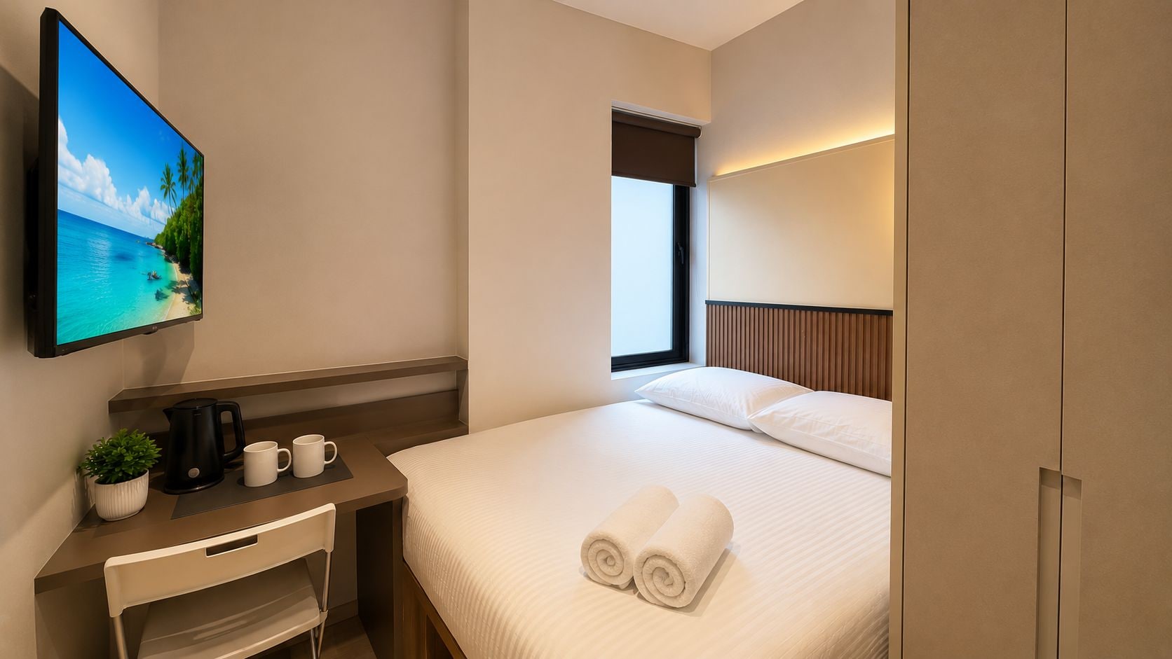 A hotel room with a bed, a desk with a coffee maker, a TV, and a window.
