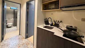 Une cuisine moderne équipée d’un four à micro-ondes, d’une cuisinière et d’un évier. On aperçoit un espace douche à l’arrière-plan.