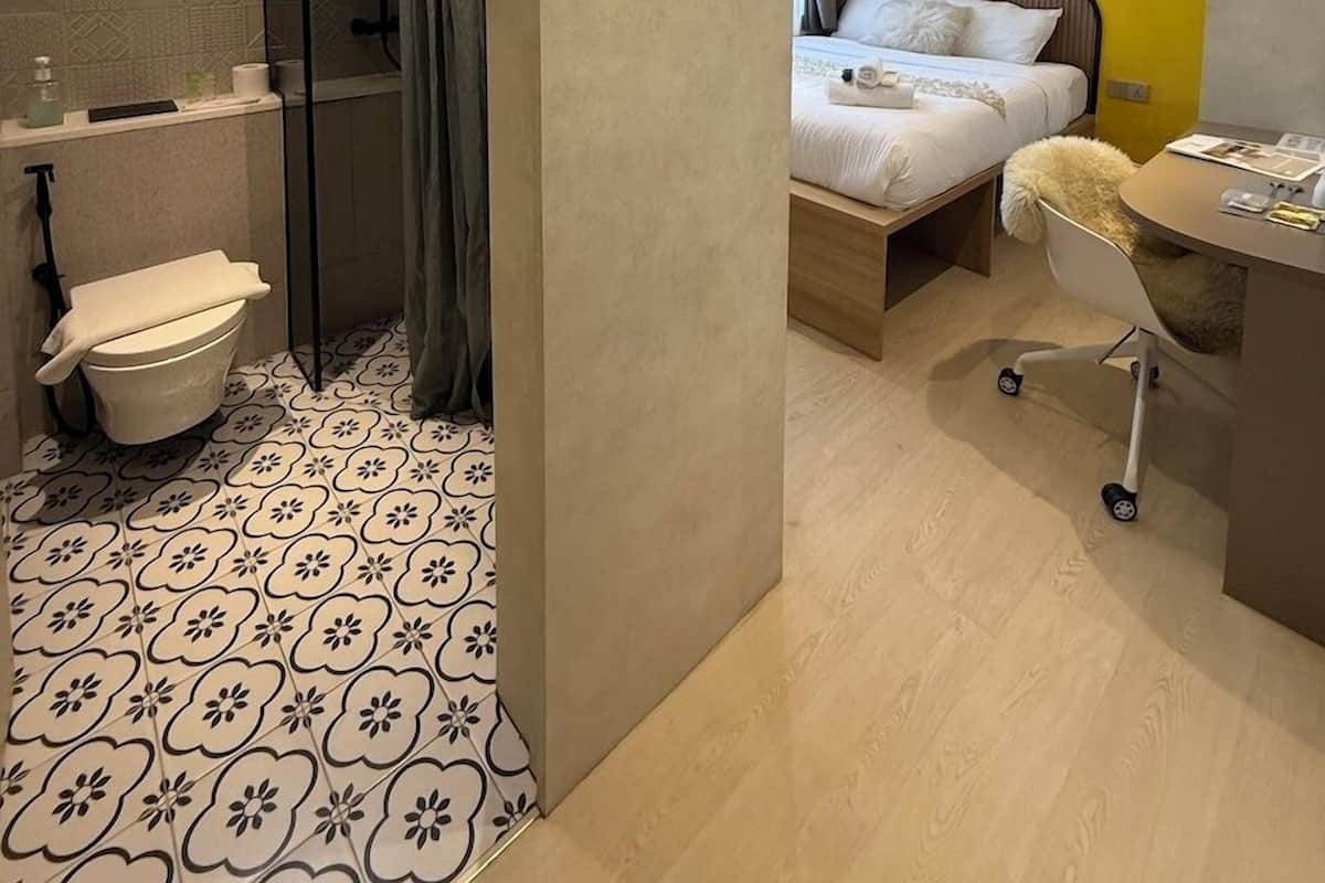 Une chambre d’hôtel moderne équipée d’une douche, de toilettes, d’un lit et d’un bureau.