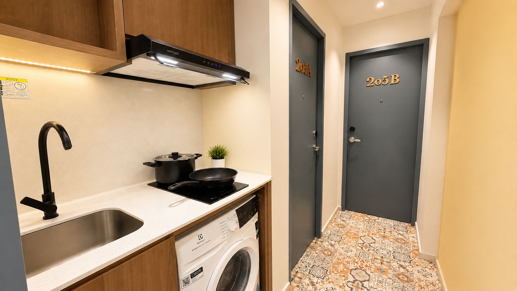 A compact kitchen with a sink, stove, and washing machine, leading to a door marked 205A.