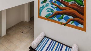 Une fresque représentant deux oiseaux perchés sur une branche, un intérieur blanc avec un plafond en verre et un banc orné de motifs.