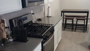 Una cocina moderna con armarios blancos, una estufa de acero inoxidable y una mesa de comedor de madera.