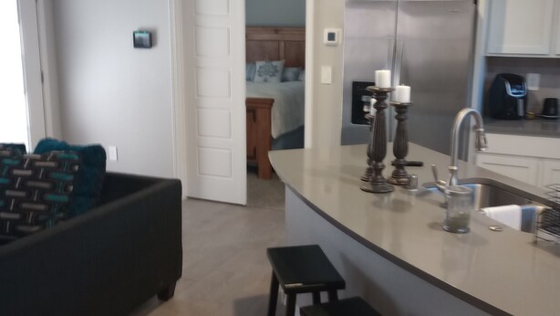 Una cocina moderna con una isla central, taburetes de bar y un refrigerador.