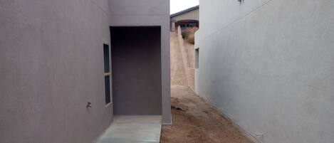 Een smal betonnen pad tussen twee gebouwen, met een onverhard pad aan één kant.