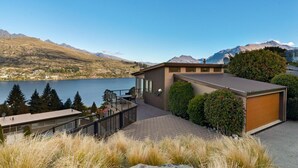 Una casa moderna con un patio che si affaccia su un lago e montagne.