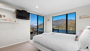 Una camera da letto con un letto grande, una TV e vista sulle montagne e un lago.