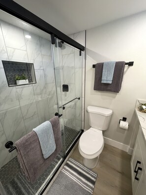 Ein modernes Badezimmer mit Duschkabine aus Glas, Toilette und Waschbecken.