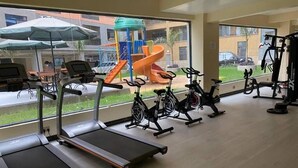 Une salle de sport équipée de tapis de course, de vélos d’appartement et d’autres appareils d’exercice.