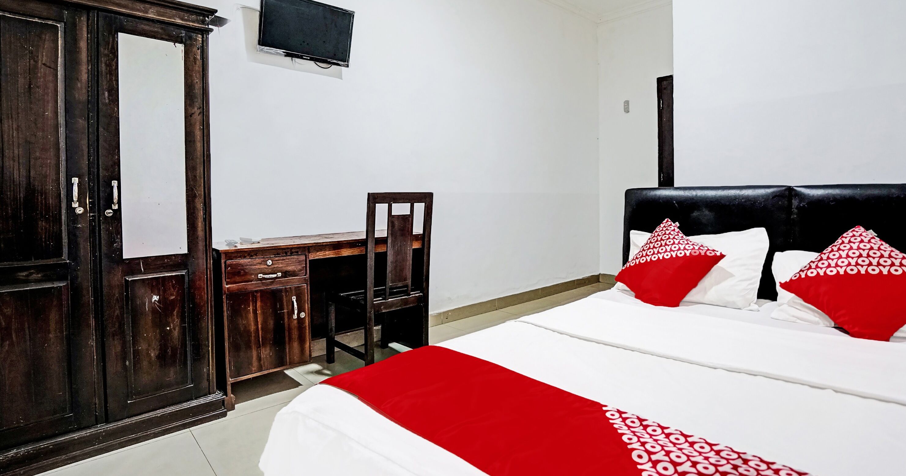 A hotel room with a bed, a desk, a chair, and a wardrobe.