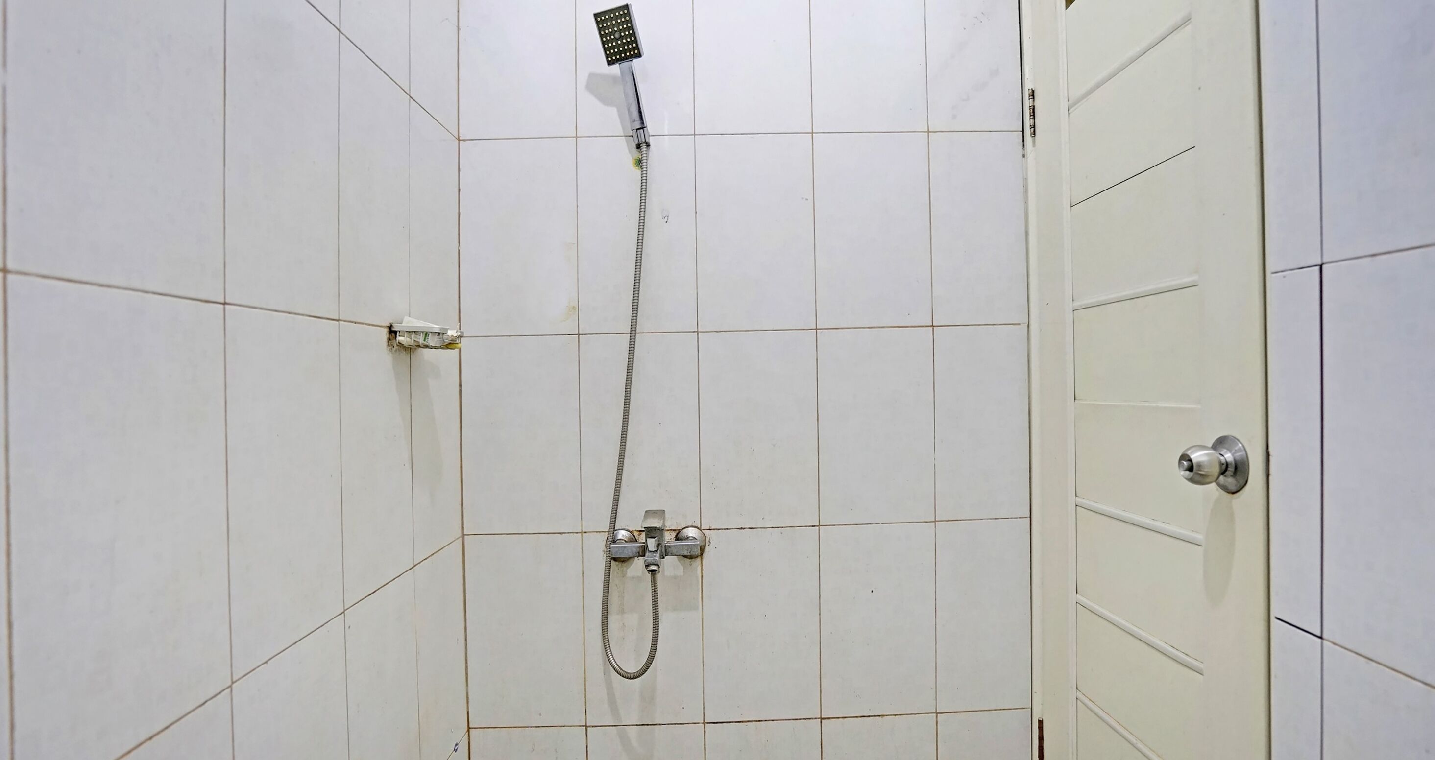 Un espace douche équipé d’un pommeau de douche à main et d’un pommeau de douche fixe fixé au mur.