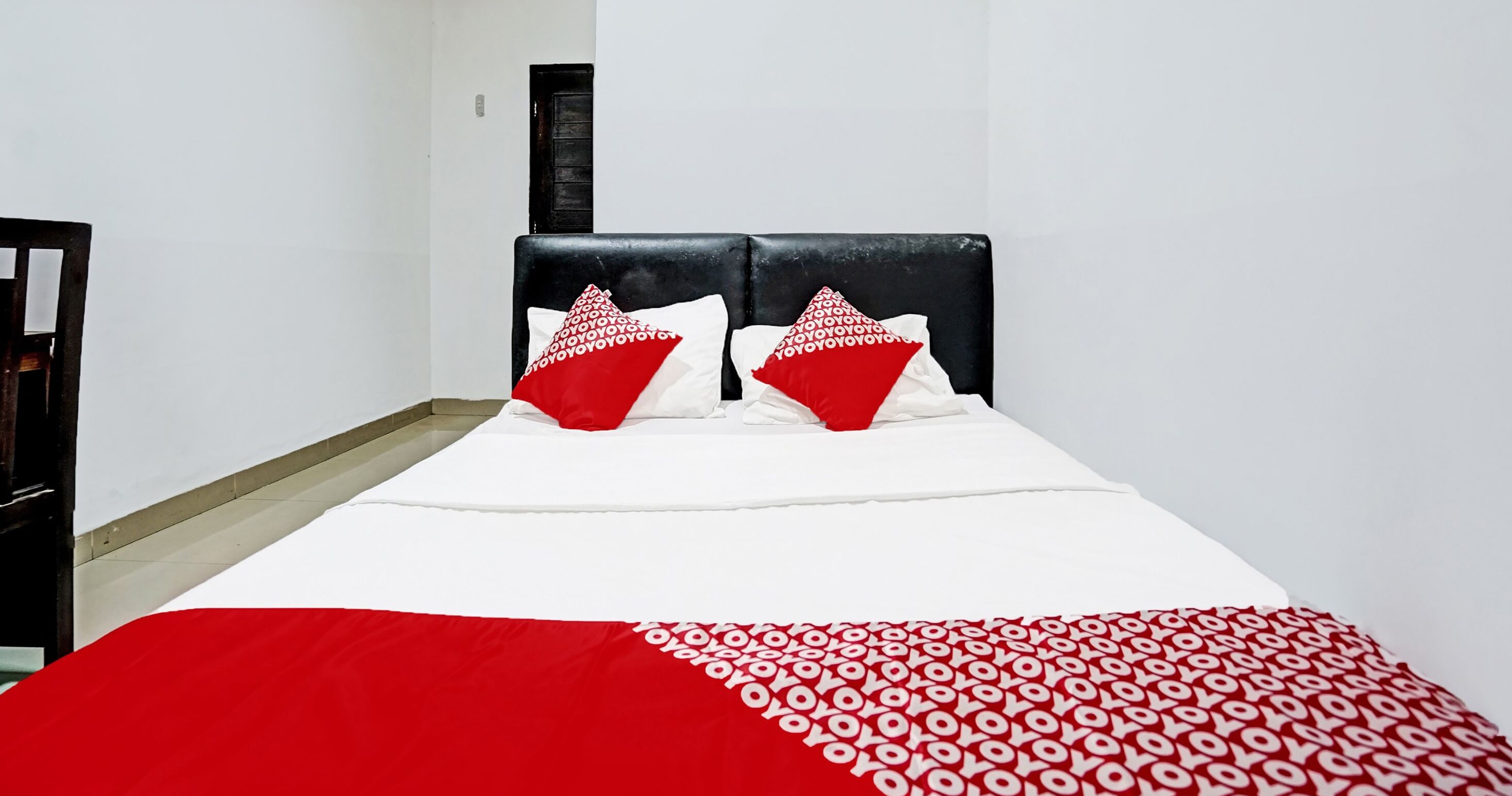 Ein Bett mit schwarzem Kopfteil, weißer Bettwäsche und roten Kissen.
