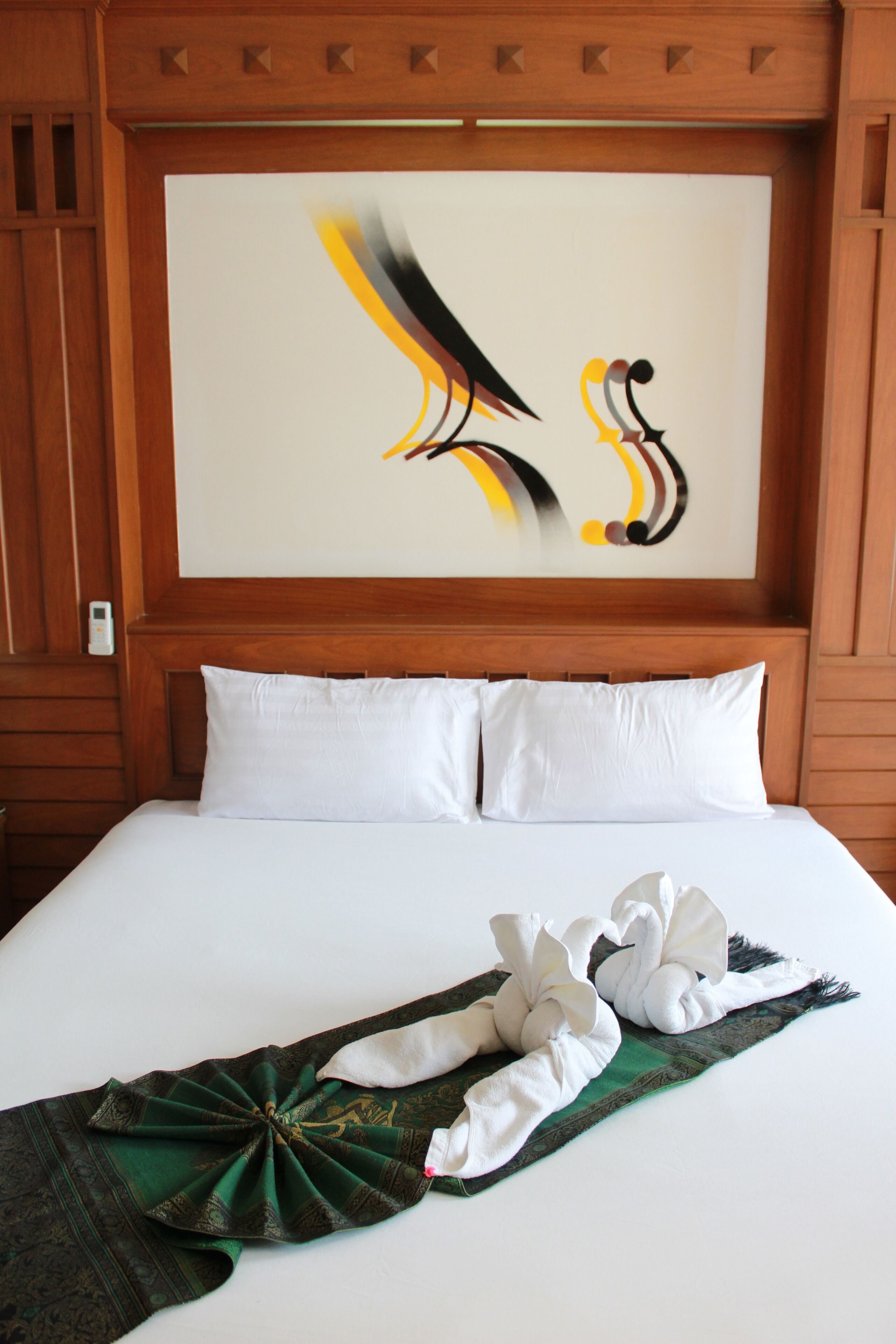 A neatly made bed with white linens and a decorative towel arrangement.