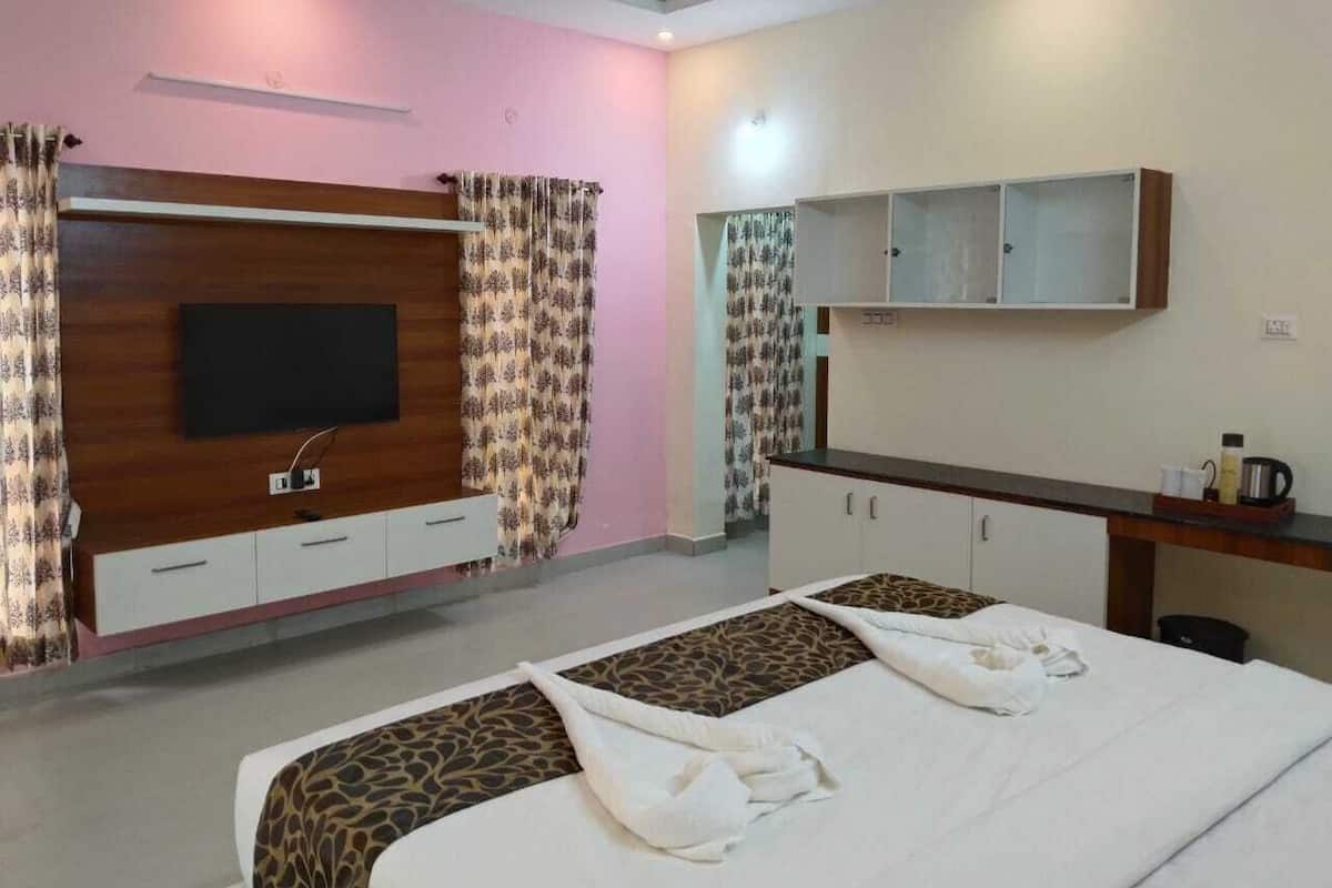 A hotel room with a large bed, a TV mounted on the wall, a minibar, and a small desk with a mirror.