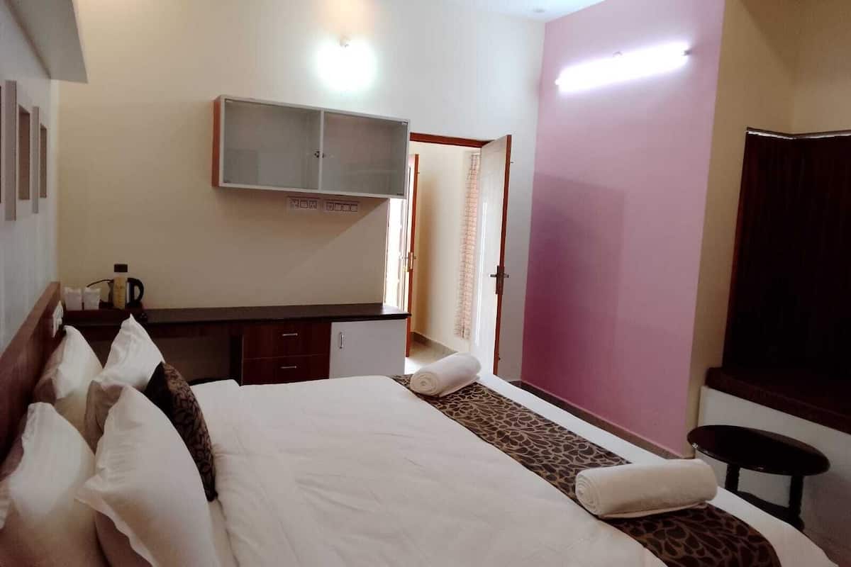 A hotel room with a bed, a small desk, a cabinet, and a mirror on the wall.