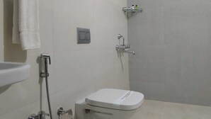 A bathroom with a toilet, a sink, and a shower. - TIO HOTELS & RESORTS - YERCAUD  (Yercaud)
