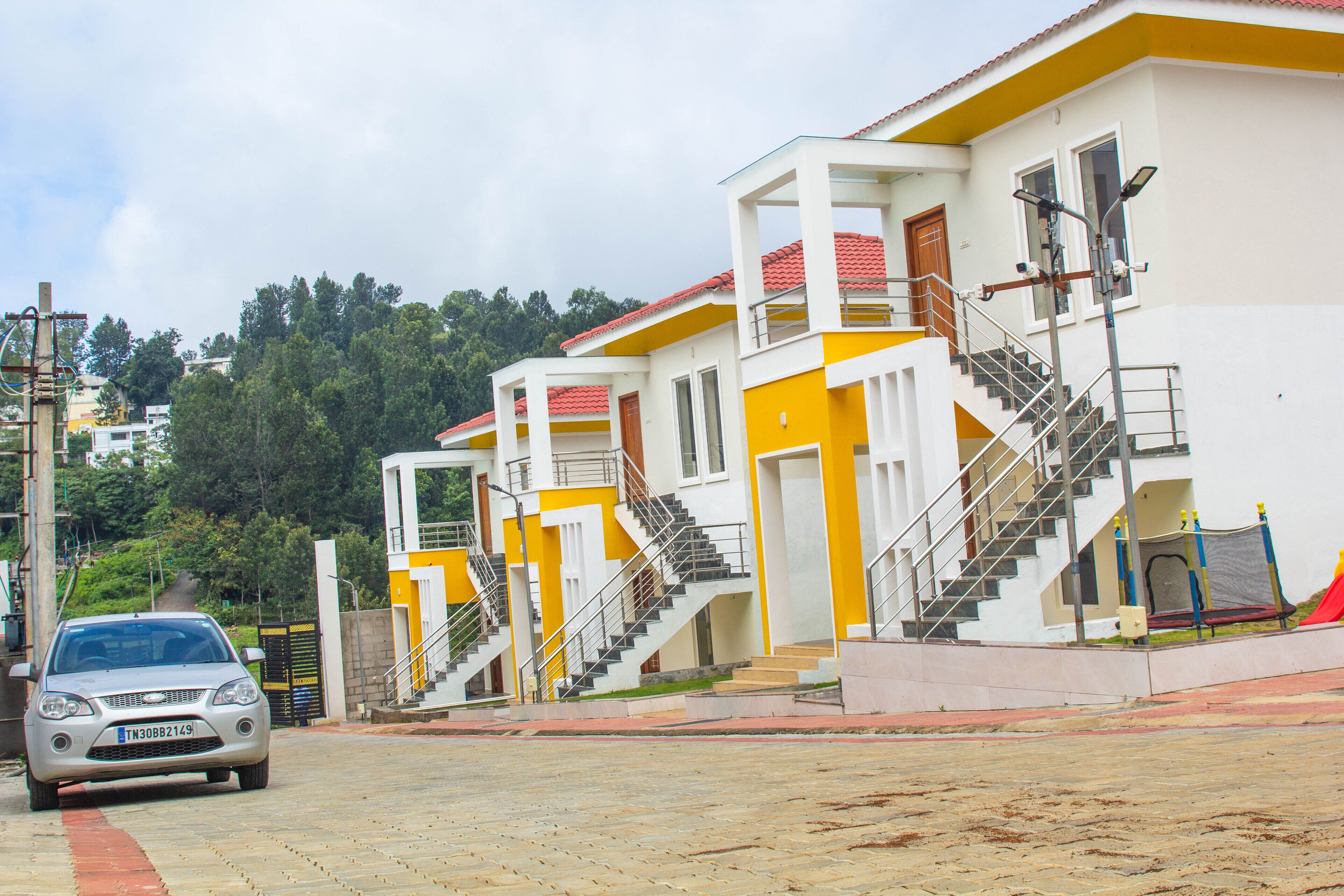 Un immeuble à plusieurs étages, à la façade jaune et blanche, avec un escalier et une voiture garée.