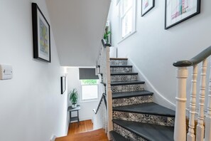 Stunning staircase with a classic handrail, framed artworks, and a potted plant.