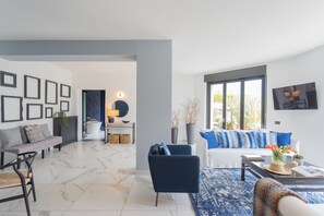 A modern living room with a sofa, armchairs, and a coffee table. There is a large window providing natural light and a view of the outdoors. - Vista Lario in Carate Urio (Carate Urio)