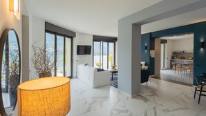 A modern living room with a large window, a sofa, a TV, and a lamp. - Vista Lario in Carate Urio (Carate Urio)