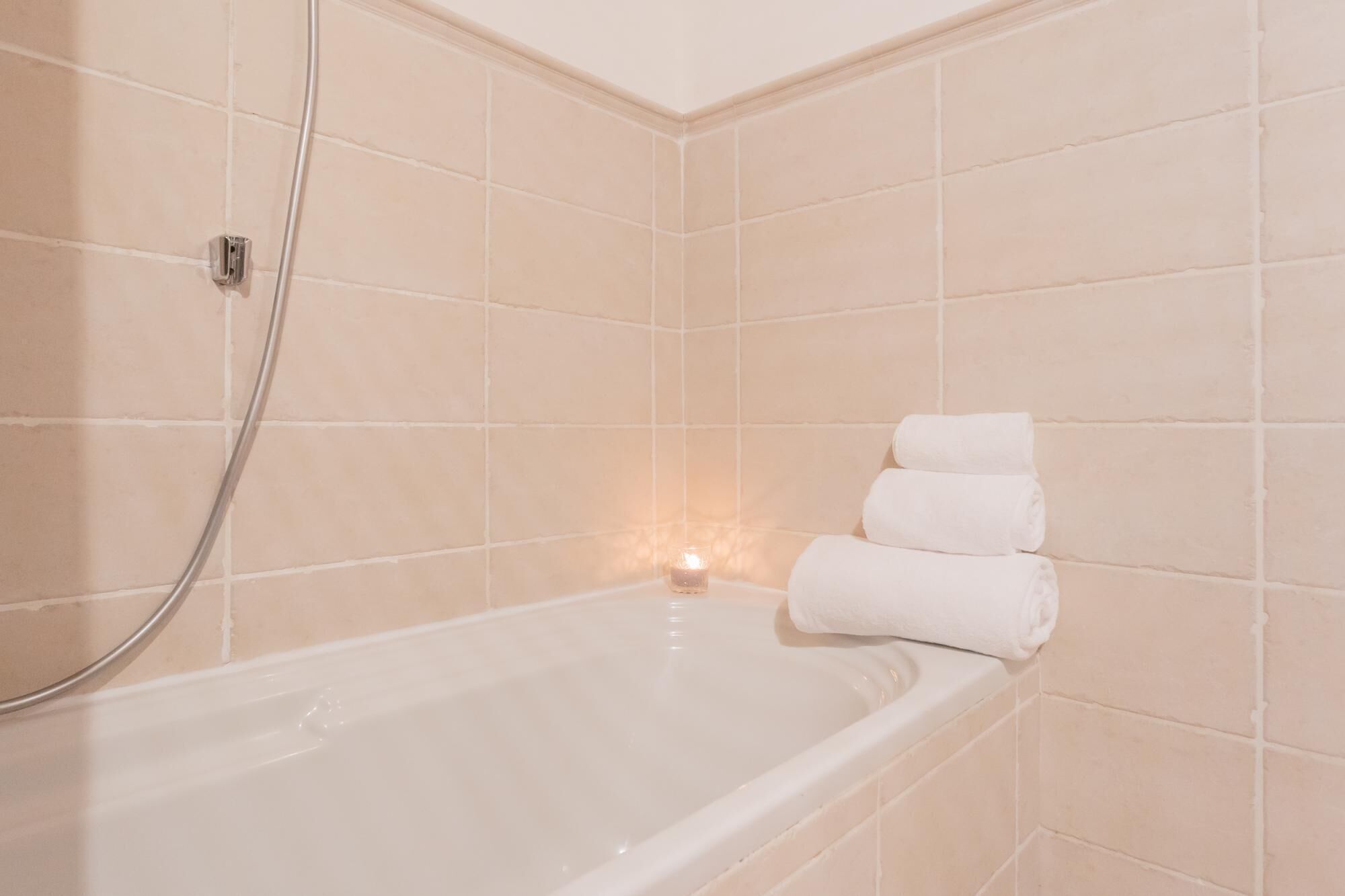 A bathroom with a bathtub, a shower, and a lit candle.