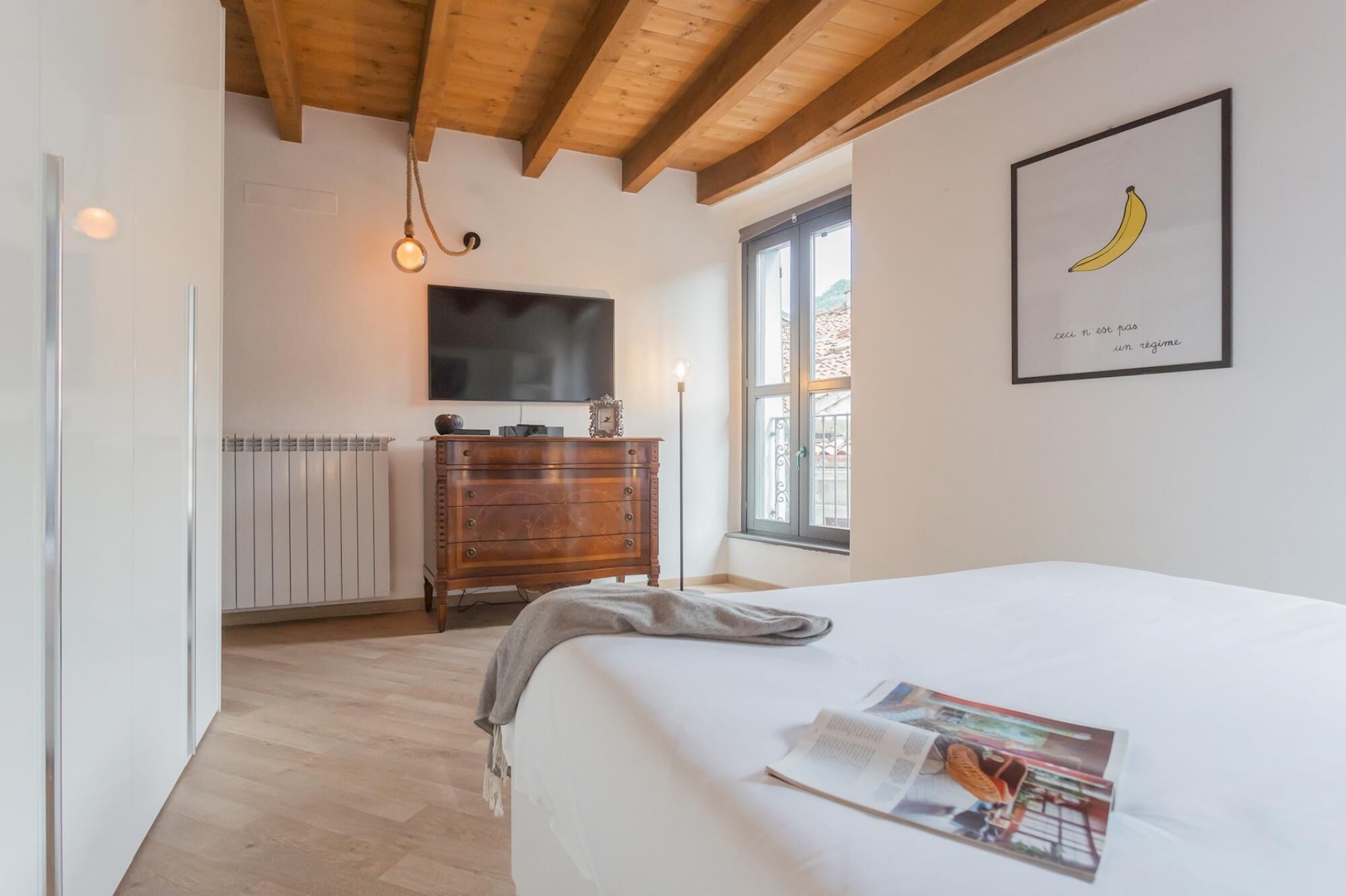 A bedroom with a bed, a dresser, a TV, and a window.