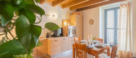 A cozy kitchen with wooden cabinets, a stove, and a dining area with a table set for two.