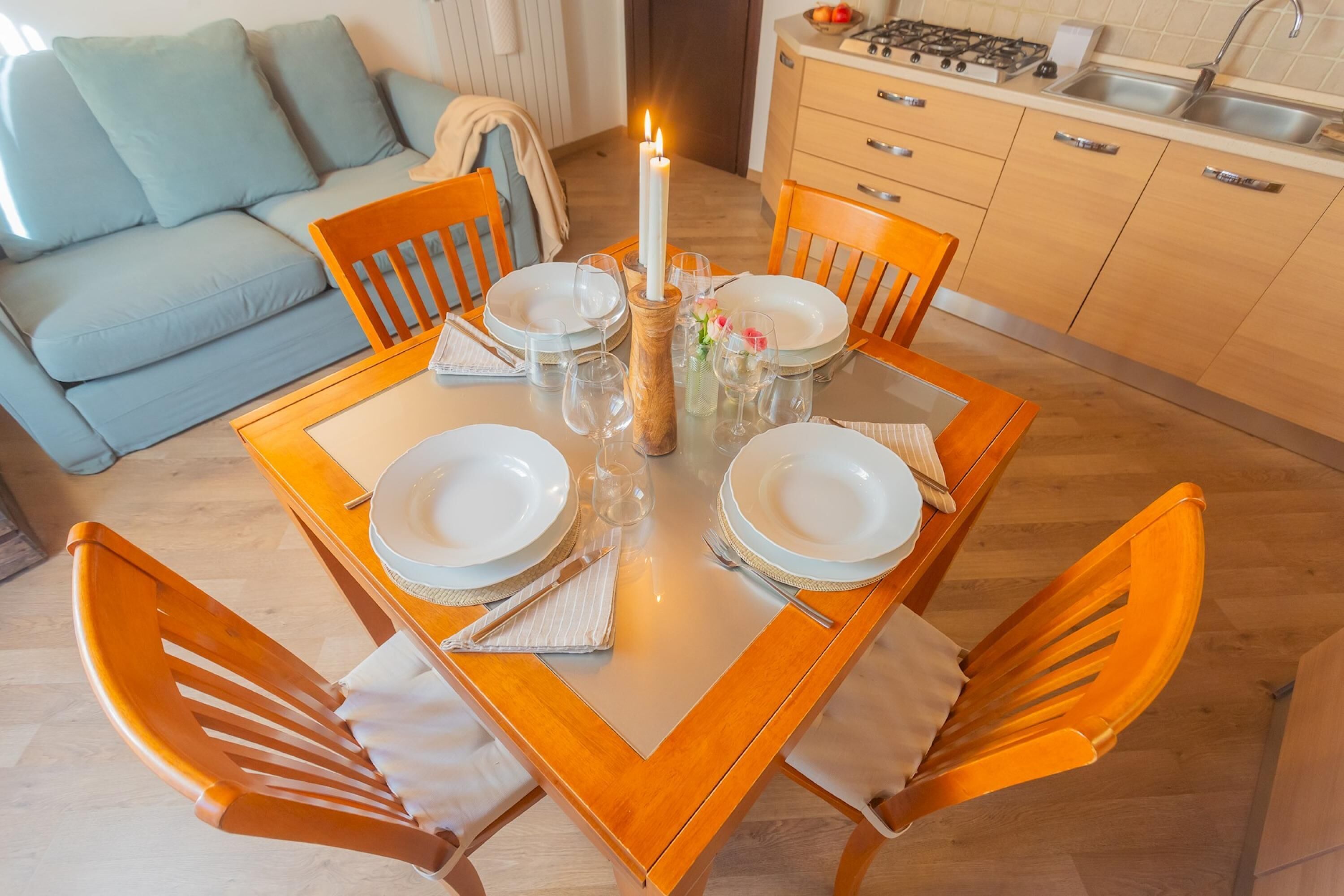 Una mesa de comedor dispuesta con platos, vasos y una vela.