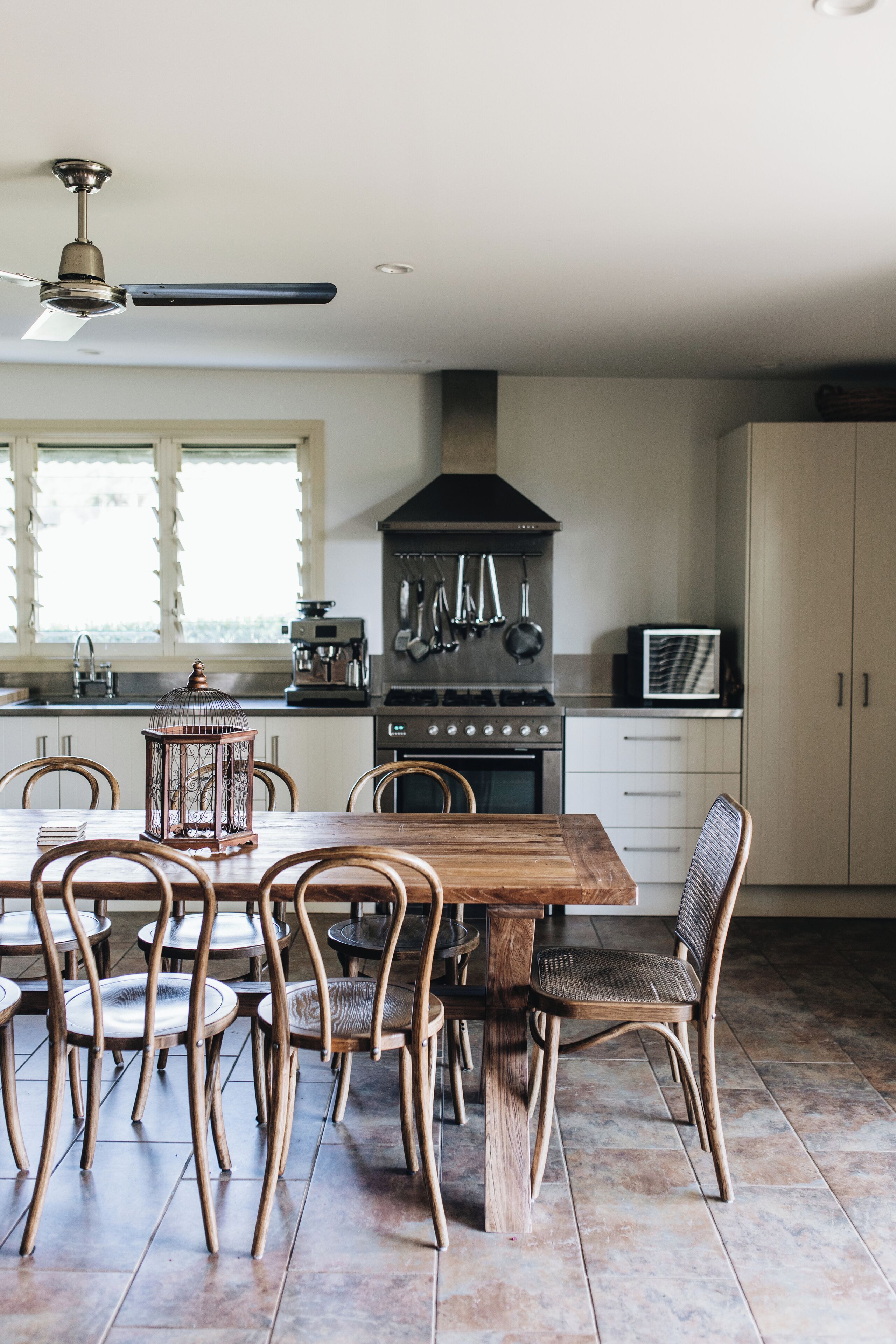 A kitchen with a dining table, chairs, and a ceiling fan.