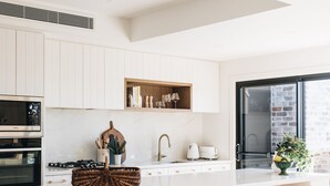 A modern kitchen with white cabinetry, a central island with stools, and a large window providing natural light.