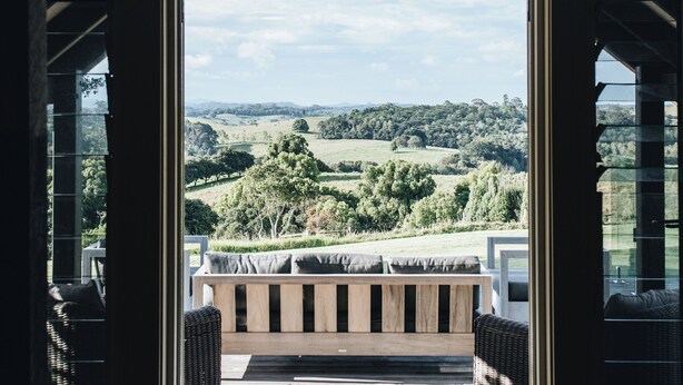 A view from a room with a large window, a stone floor, and a view of a green landscape.