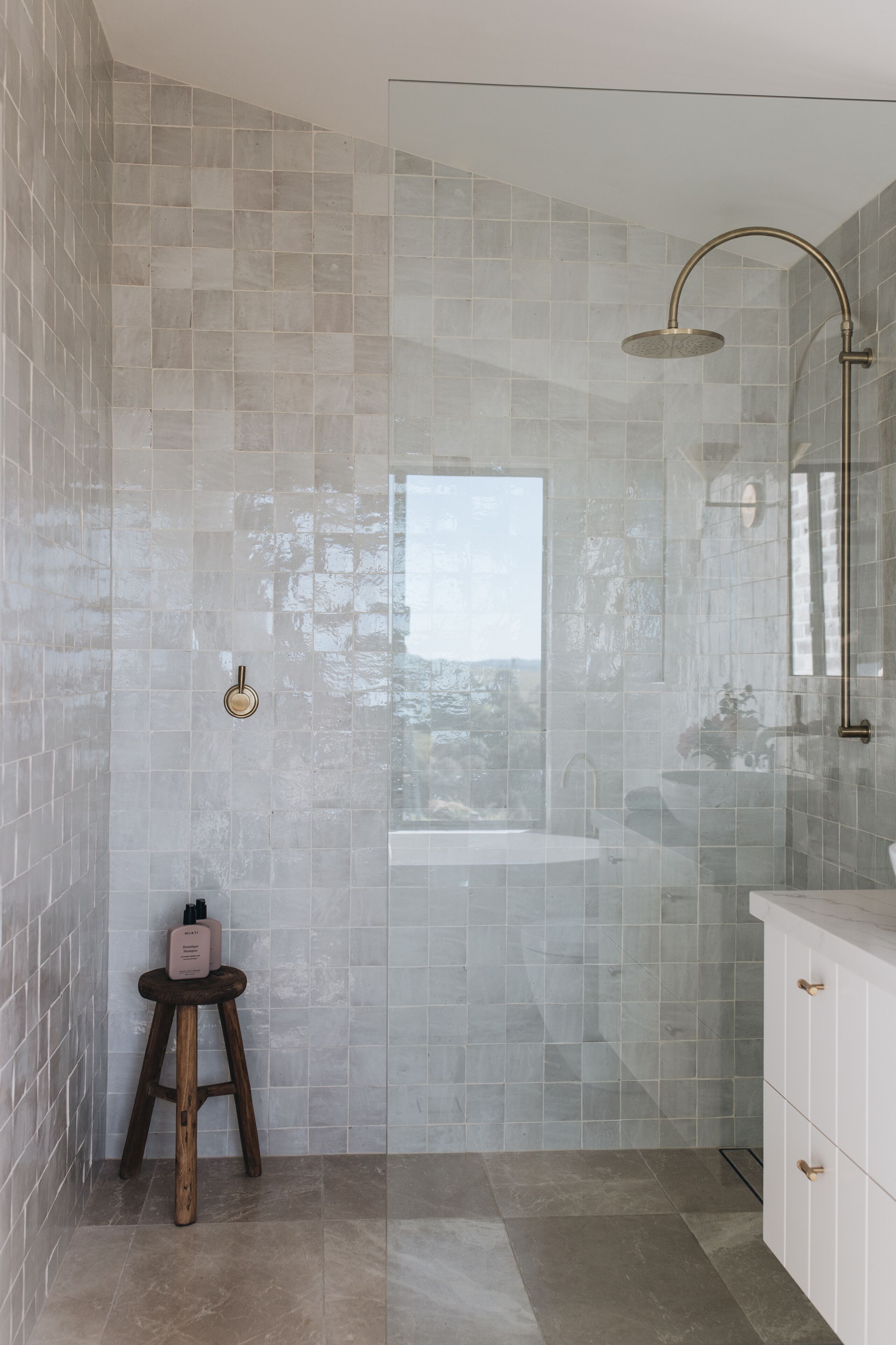 A modern bathroom with a glass-enclosed shower, a sink, and a vanity with cabinets.