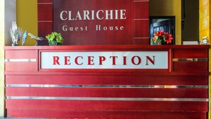 Un comptoir d’accueil avec une enseigne indiquant « RÉCEPTION » et, au-dessus, « Maison d’hôtes Clarichie ».