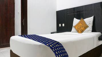 Ein Hotelzimmer mit einem Bett, einem Nachttisch, einer Holztür und einer Wand mit einer strukturierten Verkleidung.