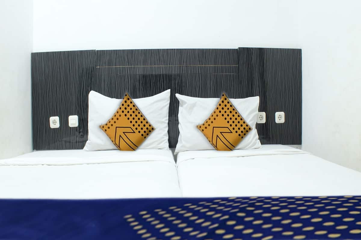 Ein Bett mit weißer Bettwäsche und zwei Kissen mit geometrischem Muster.