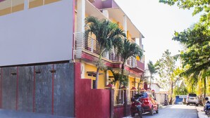 Un immeuble résidentiel à plusieurs étages, doté de balcons, d’une entrée sécurisée et de véhicules stationnés.