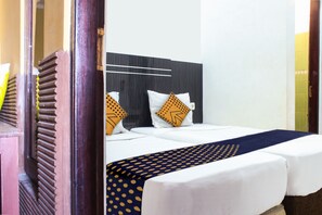 Ein Hotelzimmer mit einem Bett, zwei Kissen, einem Kopfteil und einer gemusterten Bettdecke.