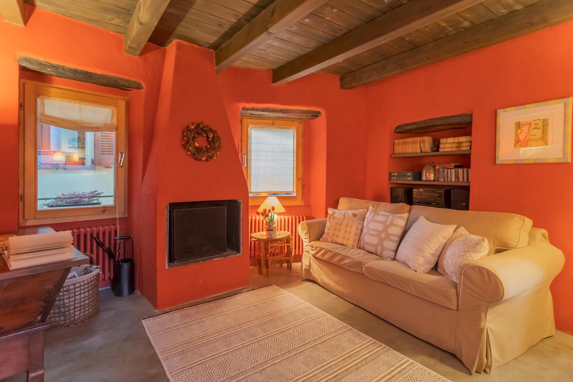 A cozy living room with a beige sofa, a fireplace, and a bookshelf.