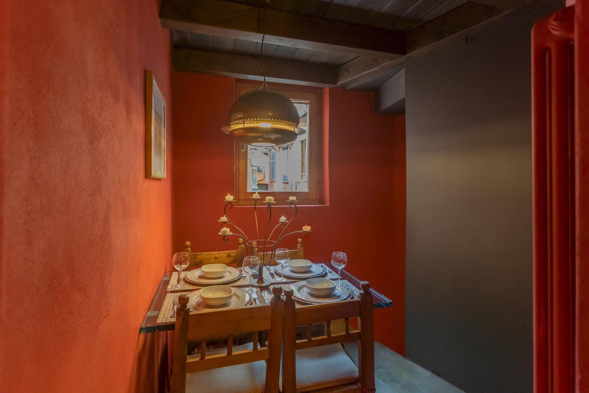 A dining area with a table set for four, a chandelier, and a window with a view.