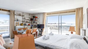 Et hotelværelse med en seng, et skrivebord, en stol, et fjernsyn og en reol.