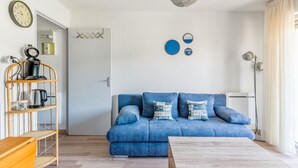 Ein modernes Wohnzimmer mit einem blauen Sofa, einem Holztisch und einer hängenden Leuchte.