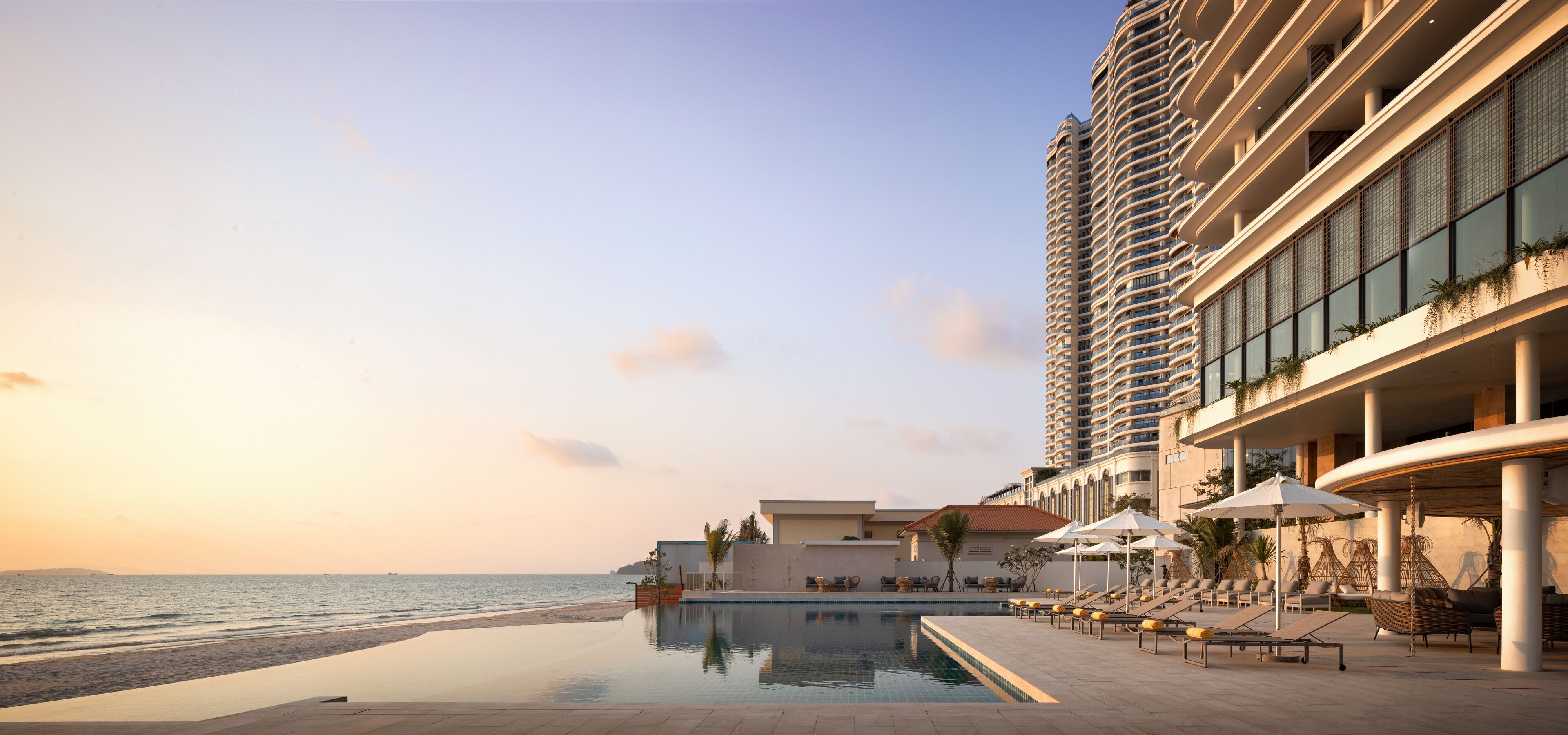 A hotel with a pool, beach view, and a high-rise building with balconies.