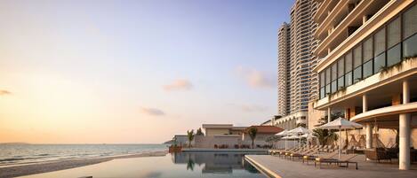 A hotel with a pool, beach view, and a high-rise building with balconies.